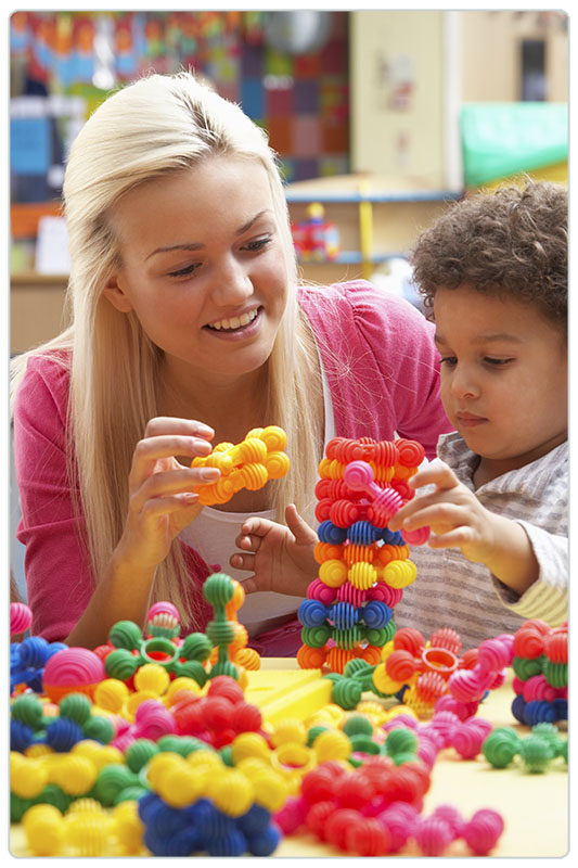 Young woman playing with boy in nursery school